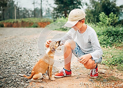 Boy met a little homeless puppy on the street Stock Photo