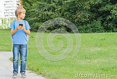 Boy with mobile phone in the street using game apps and looking around. City background. School, technology, leisure concept Stock Photo