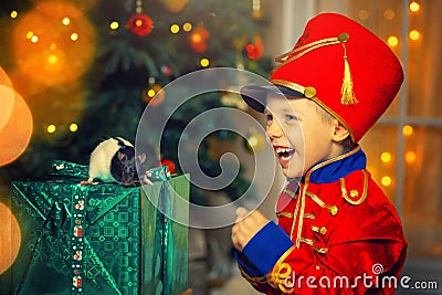 A boy in a nutcracker costume plays with the mouse symbol of the year. Stock Photo