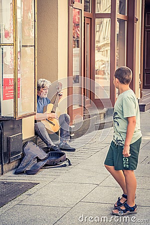 Boy observing man playing guitar in Torun Old Town Editorial Stock Photo