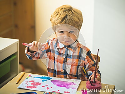 Boy is painting a picture. A beautiful child with felt-tip pens sits at the table and is engaged in creativity and art Stock Photo