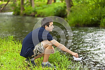 Boy with paper boat near the river Stock Photo