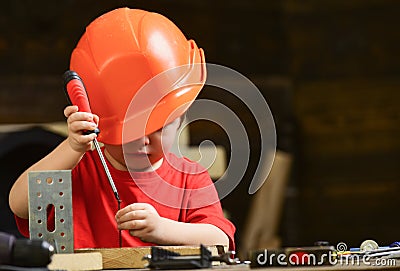 Boy play as builder or repairer, work with tools. Childhood concept. Kid boy in orange hard hat or helmet, study room Stock Photo