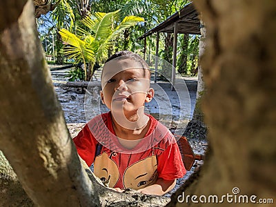 A boy is playing alone around a tree at his home. Editorial Stock Photo