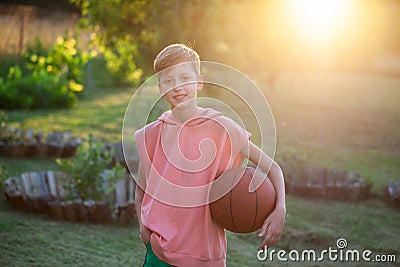 Boy playing basketball. Child holding a tball in his hands on a sunset summer day Stock Photo