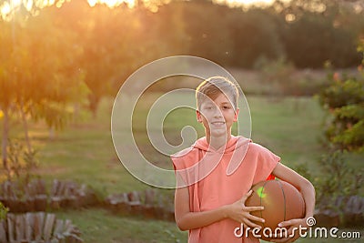 Boy playing basketball. Child holding a tball in his hands on a sunset summer day Stock Photo