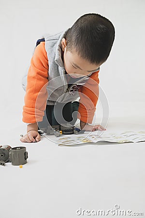 Boy playing bricks toy with instruction Stock Photo