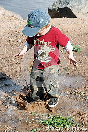 Boy playing in mud puddle Stock Photo