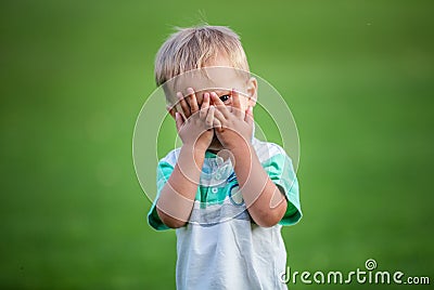 Boy playing peek-a-boo outdoors Stock Photo