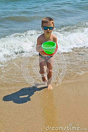 The boy is playing at sea with a bucket. Little boy having beach fun Stock Photo