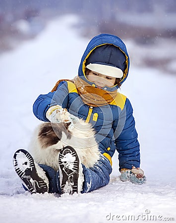 Boy plays with cat outdoors in winter, child petting kitten sitt Stock Photo