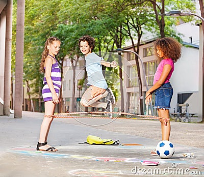 Boy plays elastics with friends outside Stock Photo