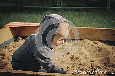 A boy plays in the sand in the sandbox Stock Photo