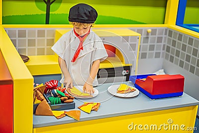 The boy plays in the toy kitchen, cooks a pizza Stock Photo