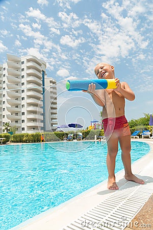 A boy plays with a water pistol near the pool Stock Photo