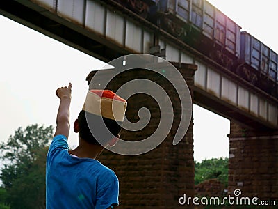 boy pointing finger towards train on blur background Editorial Stock Photo