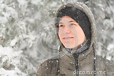 a boy is posing with snow on the street, it is snowing, a blizzard and frost on a winter day Stock Photo