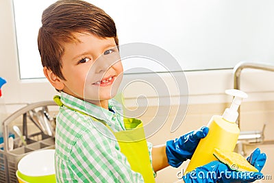 Boy pouring dish soap on sponge in the kitchen Stock Photo