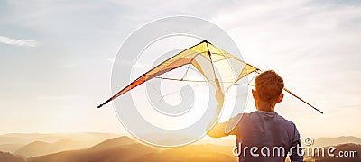 Boy prepare start to fly a kite over the sunset mountain hills Stock Photo