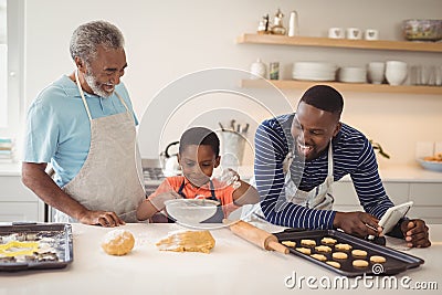 Boy preparing cookie dough with his father and grandfather in kitchen Stock Photo