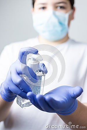 Boy with protective mask and blue gloves washing yours hands with alcohol during coronavirus quarantine Stock Photo