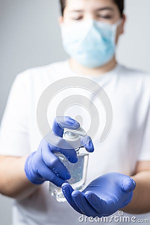 Boy with protective mask and blue gloves washing yours hands with alcohol during coronavirus quarantine Stock Photo