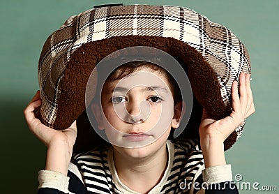 Boy put cat bed as a hat on his head Stock Photo