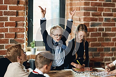 Boy with raised arms explaing the growth of business to colleagues Stock Photo