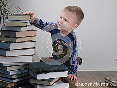The boy reaches for the stack of books Stock Photo