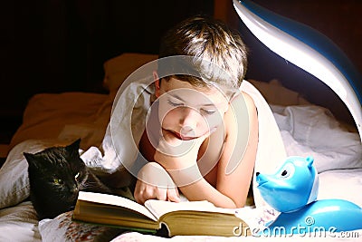 Boy read book with cat before sleeping Stock Photo