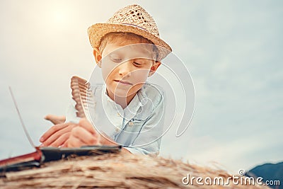 Boy reads a book lying on hay roll Stock Photo