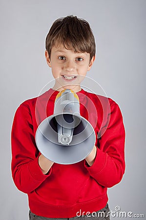 Boy in red pullover holding loudspeaker on bright background Stock Photo