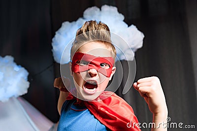 Boy in red superhero costume with fighting gesture screaming Stock Photo