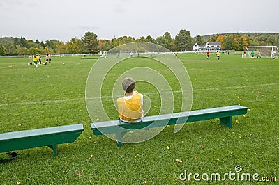 A boy rests on a bench during school soccer practice, New Hampshire Editorial Stock Photo