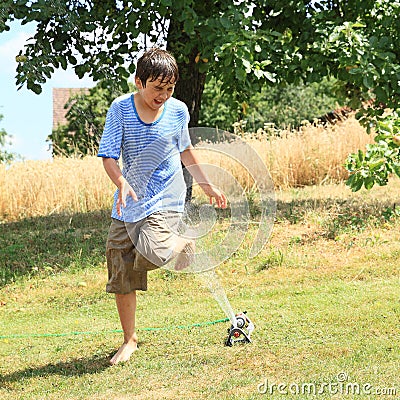 Boy running thru sprinkler Stock Photo