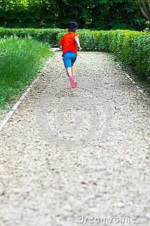 A boy running on the track surrounded by green bushes Editorial Stock Photo