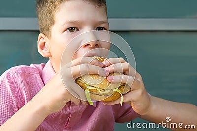 The boyâ€™s hands are holding a large meat sandwich before biting it Stock Photo