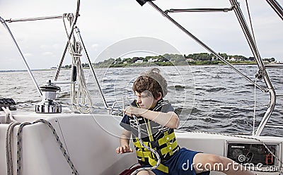 Boy sailing pulling ropes to adjust sails on sailboat Stock Photo