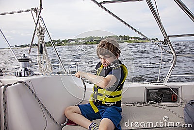 Boy sailing pulling ropes to adjust sails on sailboat Stock Photo