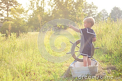 Boy in sailor suit in boat on grass Stock Photo