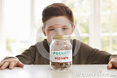 Boy Saving Pocket Money In Glass Jar At Home Stock Photo