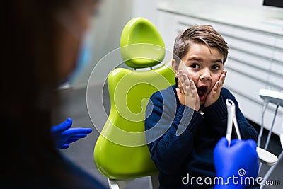 Boy scared of dentist with forceps. Ð¡hild is afraid to remove tooth. Teen refuses to treat teeth. Stock Photo