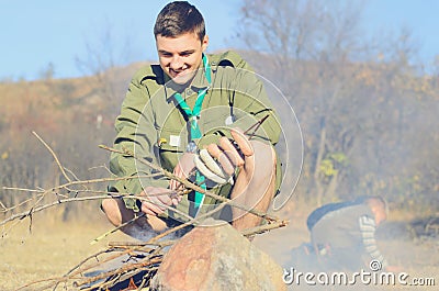 Boy Scout Cooking Sausages on Stick over Campfire Stock Photo