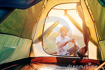 Boy sets up touristic tent ob sunset forest glade Stock Photo