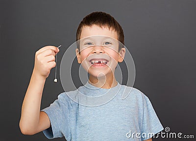 Boy show lost tooth on thread Stock Photo