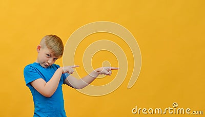 The boy shows a finger to the place for an inscription on a yellow background. Space for text, advertising, free space Stock Photo