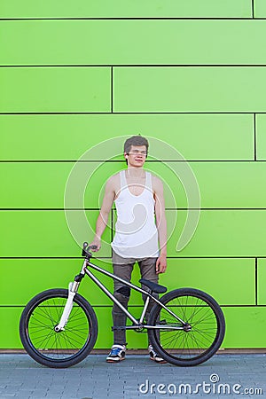 Boy with silver bike stay at green wall background Stock Photo