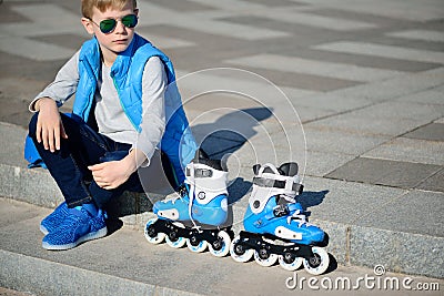 Boy siting with inline roller skates at outdoor skate park Stock Photo