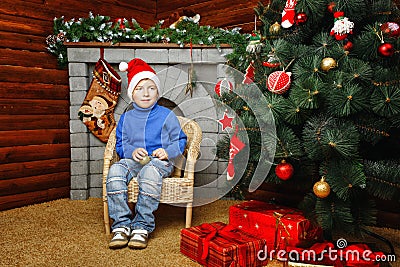 Boy sits near Christmas tree and gifts Stock Photo