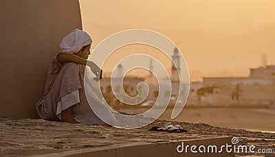 Boy sits next to a wall watching the sunset Editorial Stock Photo